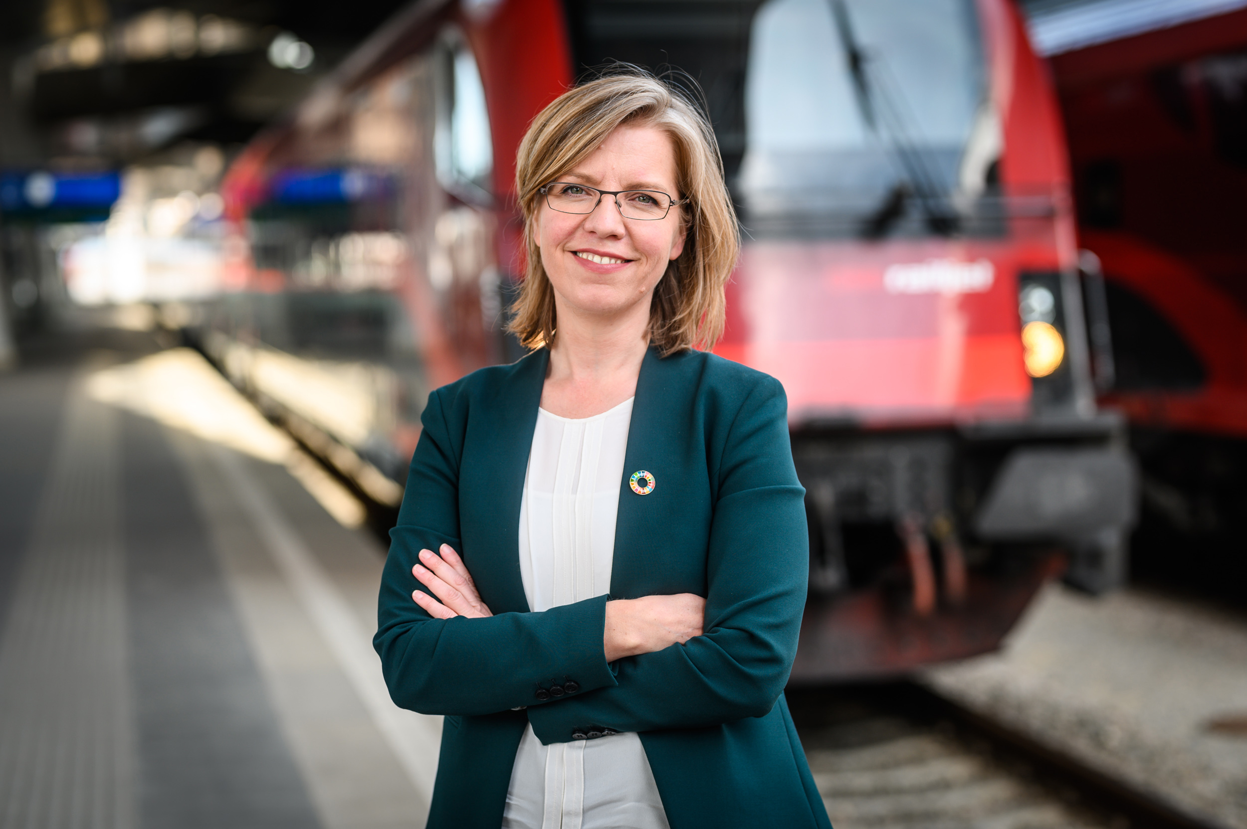 Bundesministerin Leonore Gewessler am Bahnhof vor einem Zug