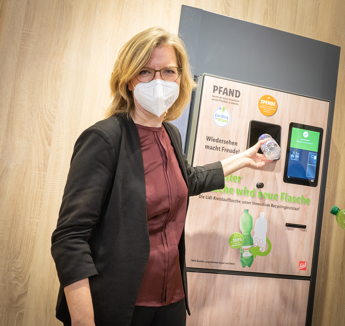 Bundesministerin Leonore Gewessler befüllt einen Rückgabeautomat für Plastikflaschen