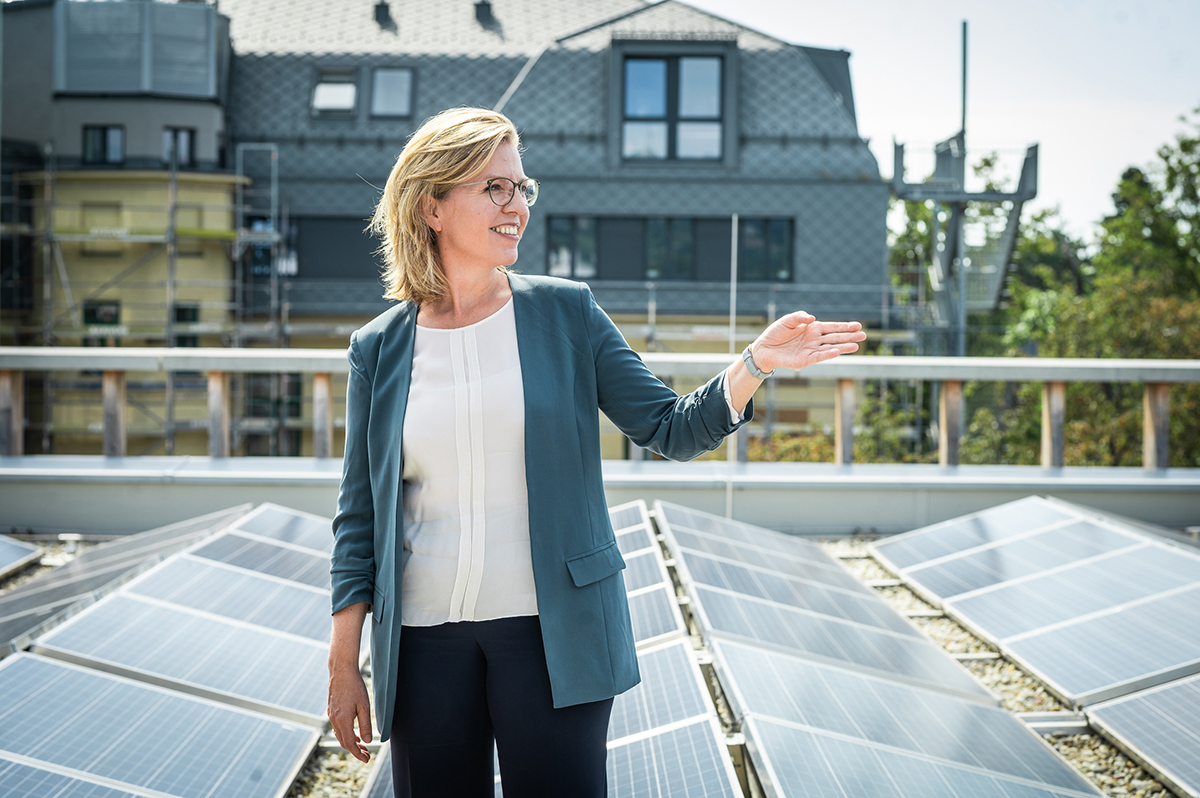 Bundesministerin Leonore Gewessler vor einer Photovoltaik-Anlage auf einem Dach